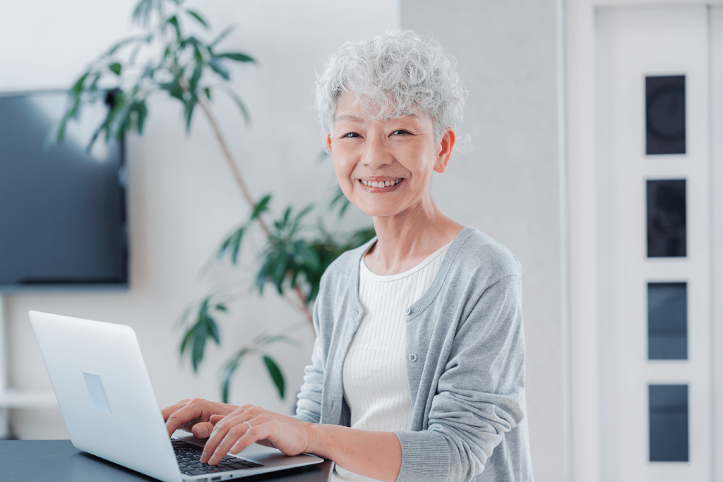 笑顔でパソコン作業するシニア女性スタッフ